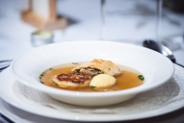 Suppe in einem weißen Porzelan Teller auf einem weiß gedeckten Tisch.