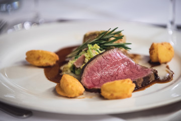Fleisch mit Kartoffeln, auf einem weißen Porzellan Teller auf weiß gedecktem Tisch.