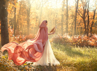 bright summer photo of mysterious beauty in morning forest, lady in shiny white dress and peach pink cloak with long train and hood, back to camera and turned face, girl with dark hair and barn owl