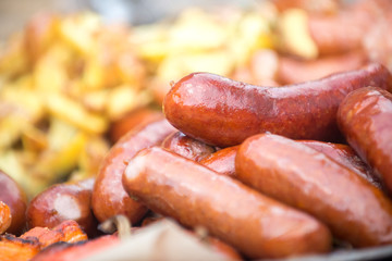 Sausages grill close-up, potatoes in a rustic style. The concept of fast-food restaurants and street fairs.