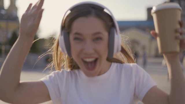 I am happy and free! funny girl walking in the city, early morning. woman in big headphones dancing and singing 4K