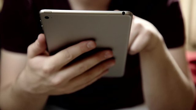 Medium shot on a young Caucasian man using a tablet.