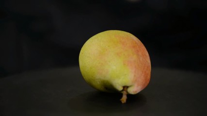 Close-up of a ripe juicy pear rotate on a black background. - Powered by Adobe