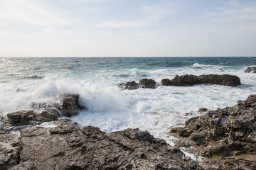 Sea waves crashing against the rocks. Day