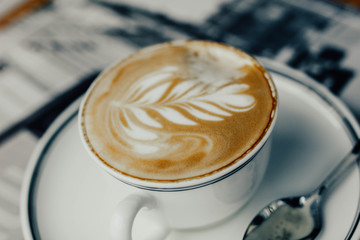 beautiful cappuccino coffee in a cup with a pattern on a foam in the form of twigs