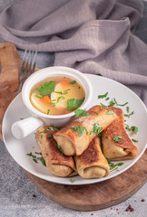 Minced meat rolled crepes served with broth. Russian cuisine
