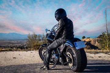 Obraz premium A biker and his bike posing while the sunset.