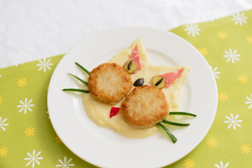 Baby puree in the form of a cat. Mashed potatoes. Children's menu on a green background.