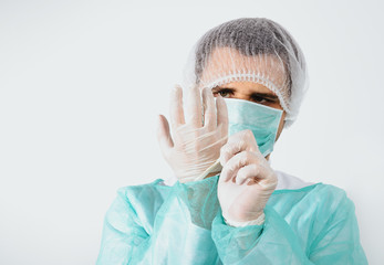 Preparing for surgery, dressing the surgeon. A man wearing a green surgical apron and a face mask on a light background. Medical and pharmaceutical concept. Saving lives.