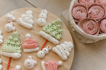 Christmas treats on a wooden table. Christmas sweets from bese in the form of a snowman, Christmas trees and Santa Claus hats