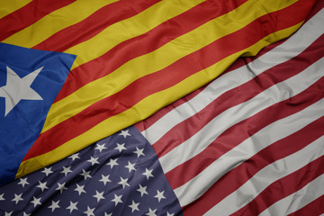 waving colorful flag of united states of america and national flag of catalonia.