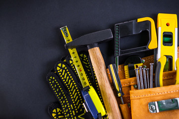 Tools in the bag for carpentry and accessories on a black background.