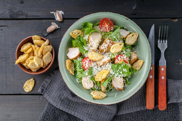 Close-up Caesar salad with fried chicken, parmesan and croutons on a dark rustic background. Top view