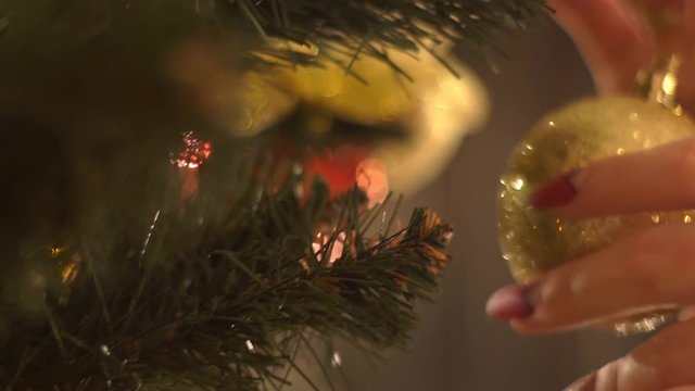 Closeup Image Of Female Hands Putting Bauble On Christmas Tree.