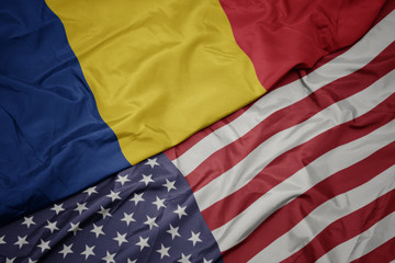 waving colorful flag of united states of america and national flag of romania. macro