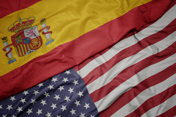 waving colorful flag of united states of america and national flag of spain. macro