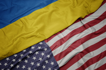 waving colorful flag of united states of america and national flag of ukraine. macro