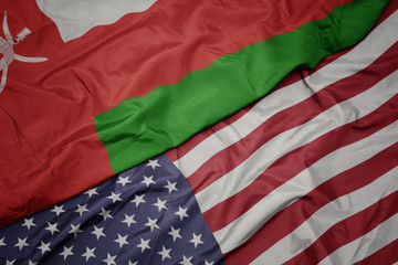 Obraz premium waving colorful flag of united states of america and national flag of oman.