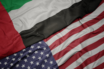 waving colorful flag of united states of america and national flag of united arab emirates.