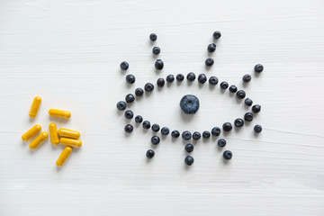 Conceptual photo of the treatment of vision. Products that improve vision. Blueberries and vitamins for eye health. View from above.