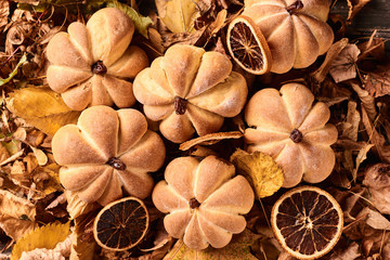 Homemade cookies in shape of pumpkin in autumn leaves. Halloween handmade cookies on a table, close up
