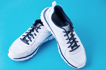 Pair of male white sneakers on a blue background. Sport shoe close up
