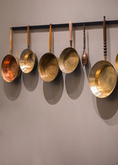 Decorative old vintage frying pans. Collection of used copper frying pans on the wall