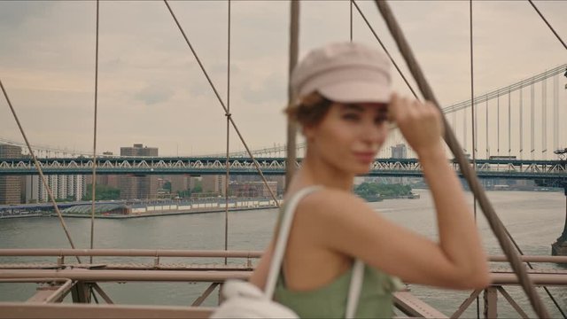 French lady walks by Brooklyn Bridge and enjoys it, first time in New York, moment from tourist's life, visiting a destination, feeling happy.