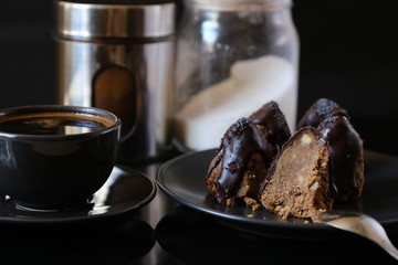 Anthill chocolate cake dessert on a gray plate and cup of coffee . Black table in the kitchen.