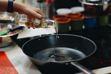 Jug pours liquid on pan. Green lettuce and purple onion. Frying pan is warming up. Need some olive oil.