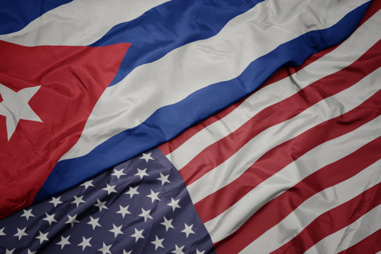waving colorful flag of united states of america and national flag of cuba.