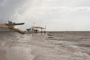 A beach flooded with water during a storm on the Sea of Azov and the embankment of the city of Primorsko-Akhtarsk in Russia on a summer day.