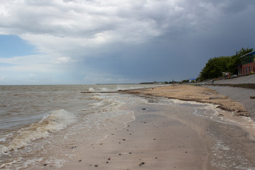 A beach flooded with water during a storm on the Sea of Azov and the embankment of the city of Primorsko-Akhtarsk in Russia on a summer day.