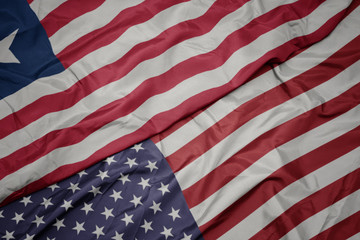 waving colorful flag of united states of america and national flag of liberia.