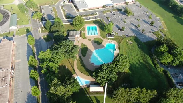 High aerial orbiting drone shot above community swimming pool with schools and Recreation Center in Lititz, Lancaster County, Pennsylvania