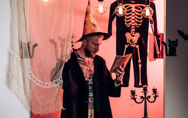 Scary hipster with beard in witch hat and plaid shirt. Magic, enchantment, witchcraft. Halloween,...