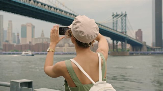 French traveler take photos of Manhattan Bridge. European girl first time visit New York. Enjoying the moment and feeling excited. Amazing industrial view.