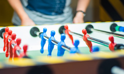 A man plays table football. Detail of man's hands playing the kicker