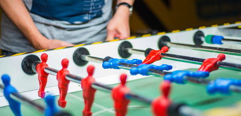 A man plays table football. Detail of man's hands playing the kicker