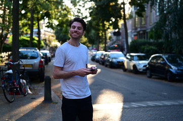 Spontaneous and happy young man smiling and texting his girlfriend on his mobile phone while standing outside