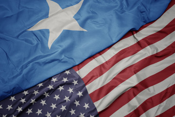 waving colorful flag of united states of america and national flag of somalia.