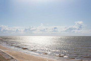 The beach is flooded with sea water after a summer storm at sea and the sun's rays.