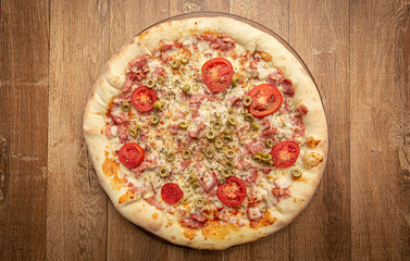 Top view of homemade pizza with tomato, olive, cheese and other ingredients.