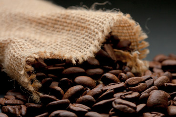 Sack of light yellow straw, with coffee beans inside the sack. On a black background.