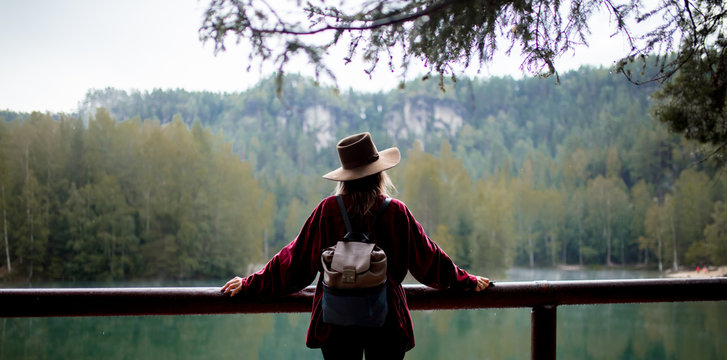 woman in hat and red shirt near lake in a mountains.