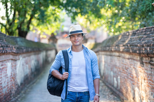 Travel and tourism. Young caucasian man traveling in the morning at temple in old city of Ayutthaya. Traveler man walking on ancient ruins street in Ayutthaya old city. Thailand.