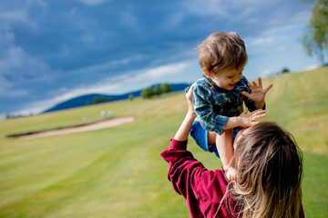 mother have a fun with a son on a meadow in mountains