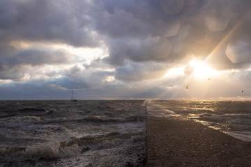 Storm on the Sea of Azov at sunset, pier and beach flood the waves on a summer evening