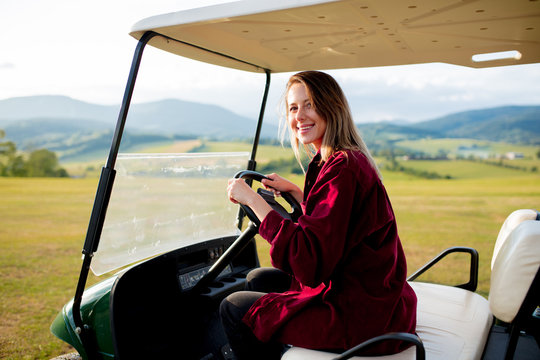 Young woman have a fun with golf buggy car on a field in mountains