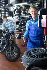 mechanic with bike wheel in workshop .